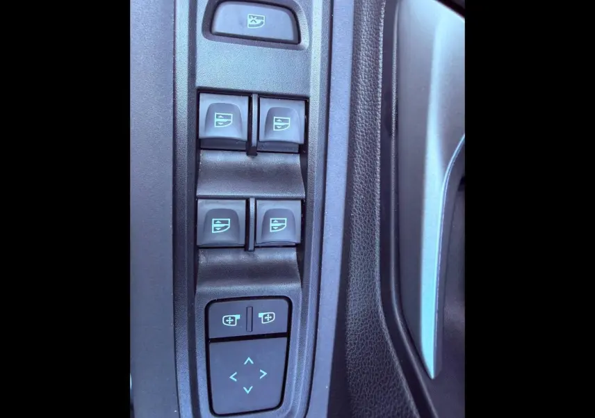 Gros plan sur les commandes de lève-vitres et réglage des rétroviseurs côté conducteur dans une Dacia Sandero 2025.