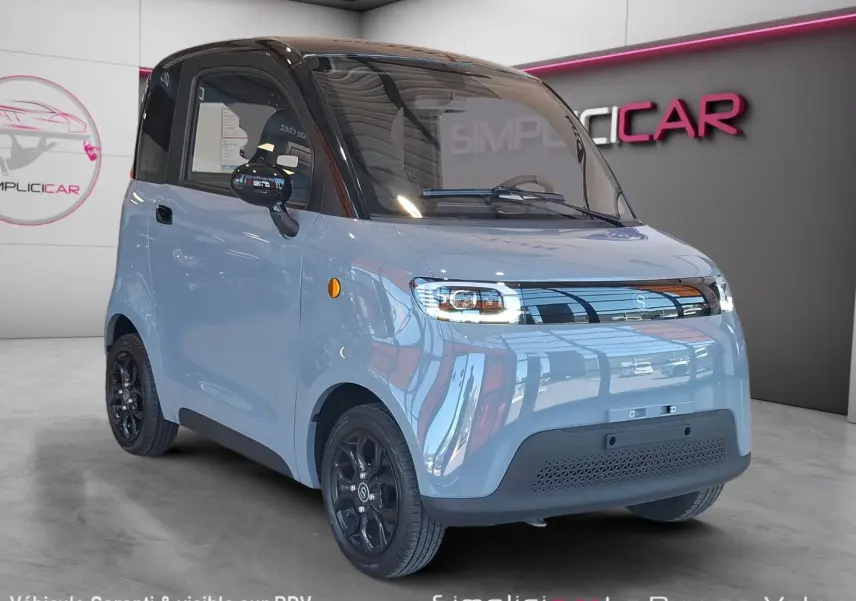 Vue 3/4 avant gauche de la Simplici S1 électrique gris perle avec toit noir et jantes noires en intérieur showroom.