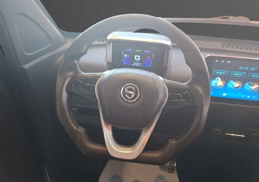 Vue rapprochée du volant noir de la SIMPLICI S1 2025 avec tableau de bord digital et écran tactile bleu.