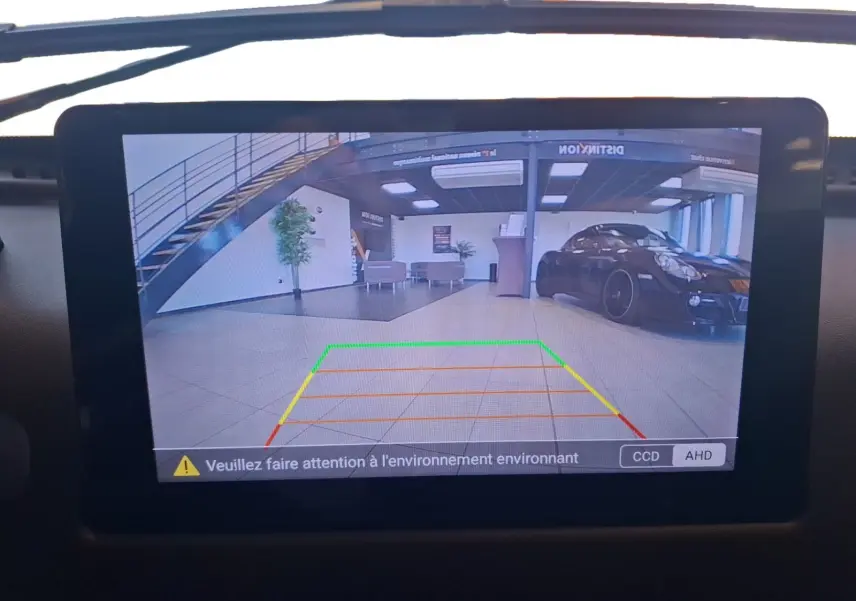 Écran de caméra de recul montrant un intérieur de garage avec une voiture noire stationnée à droite.