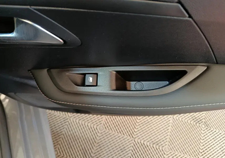 Poignée intérieure côté gauche avec commande de lève-vitre sur porte d'une Peugeot 208 gris foncé 2025.