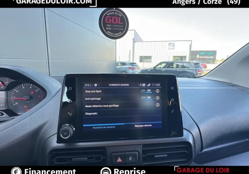 Vue intérieure du tableau de bord du Peugeot Rifter bleu 2024, avec écran tactile central affichant les réglages du véhicule.