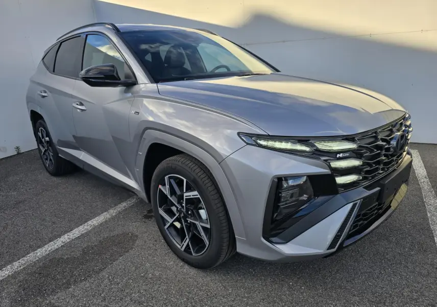 Hyundai Tucson 2025 gris argenté en vue 3/4 avant droit avec calandre N Line et jantes alliage noires.