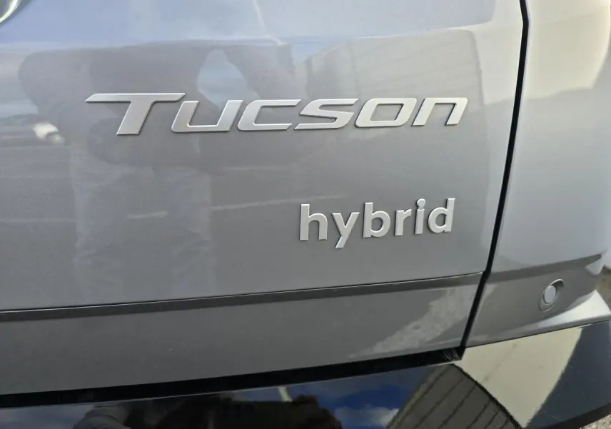 Gros plan sur l’arrière droit d’un Hyundai Tucson 2025 hybride en gris métallisé avec badges Tucson et hybrid visibles.