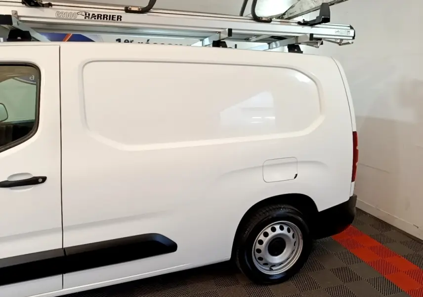 Vue latérale droite du Peugeot Partner blanc utilitaire avec galerie de toit et jantes acier en intérieur.