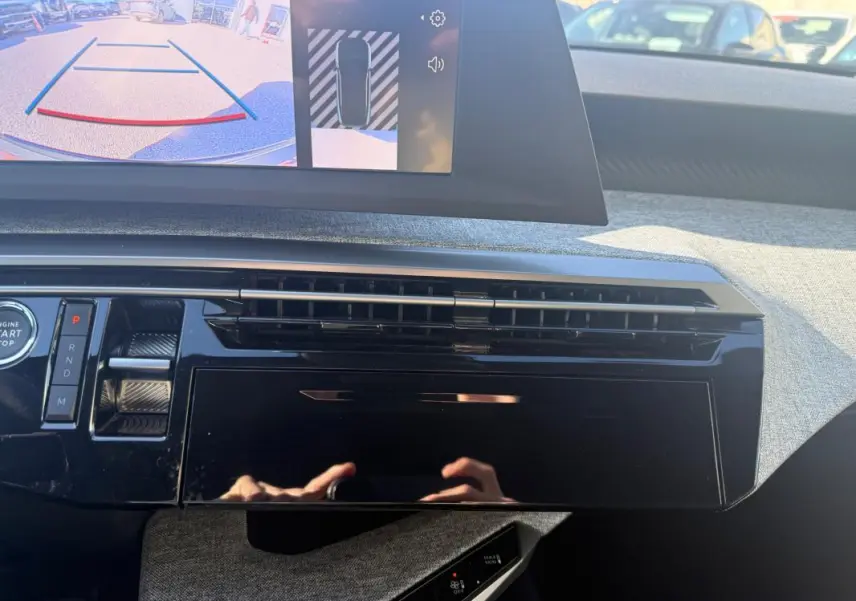 Vue rapprochée du tableau de bord noir brillant du Peugeot 3008 Hybrid 145 Allure avec écran de caméra de recul allumé.