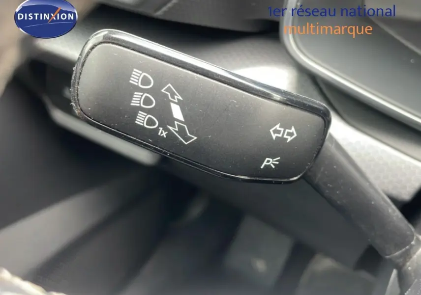 Gros plan sur la commande de clignotants et feux d’un SEAT Leon blanc neige métal 2025, intérieur gris noir.