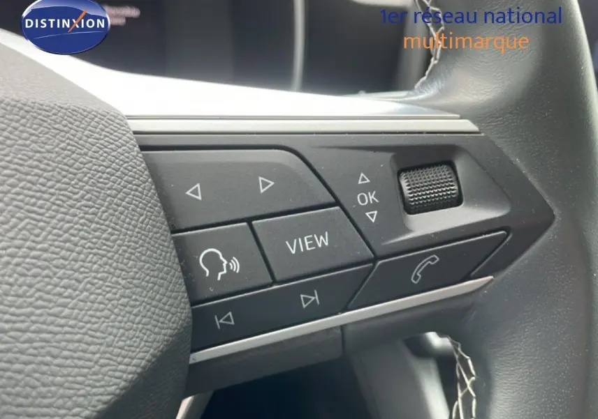 Gros plan sur les commandes multifonctions à droite du volant en cuir noir du SEAT LEON blanc neige métal.