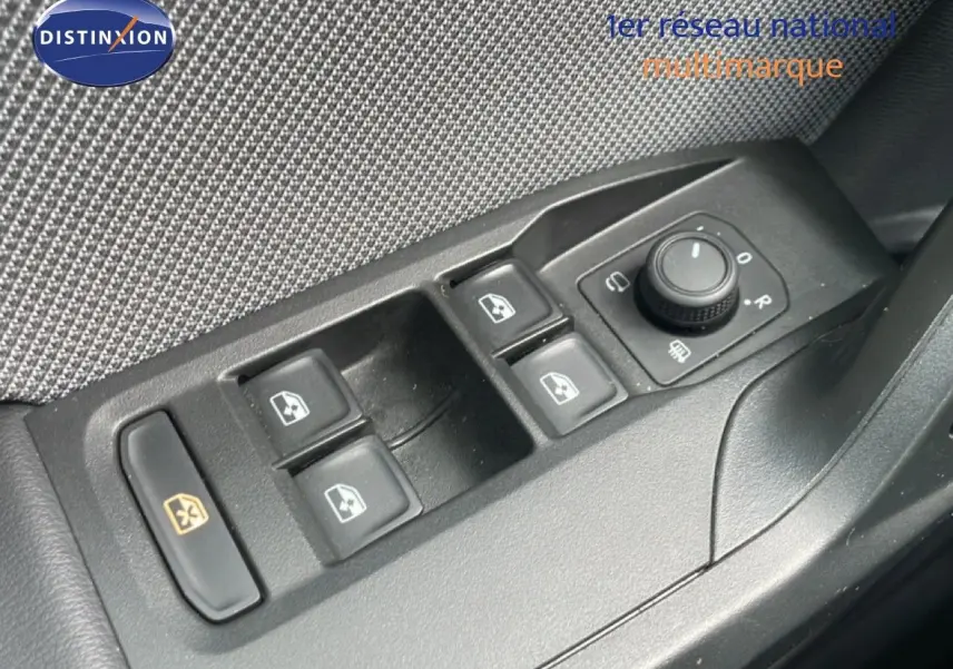 Gros plan sur les commandes des vitres électriques et rétroviseurs côté gauche d'une SEAT LEON blanc neige métal.