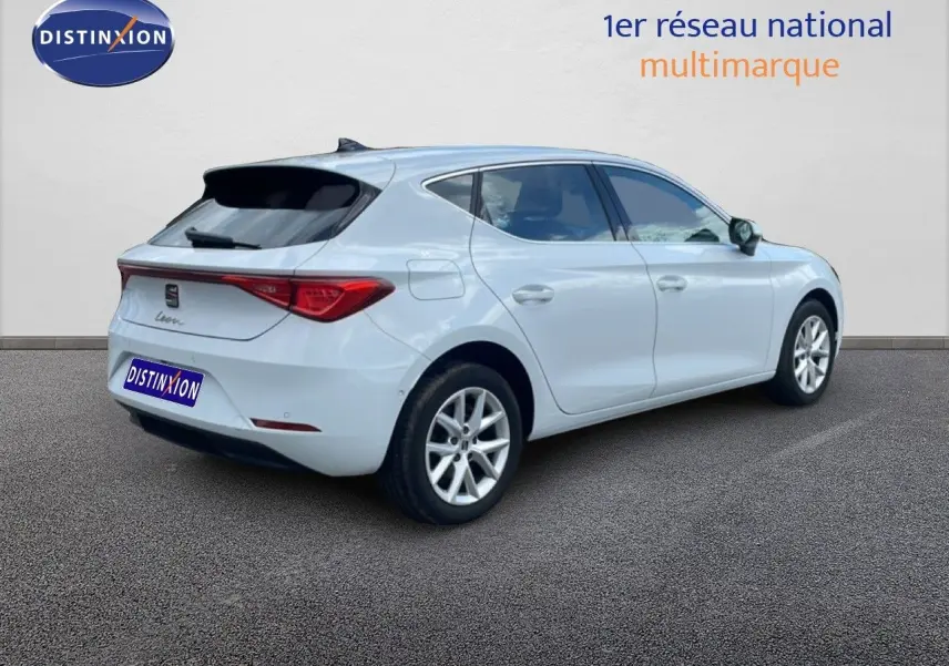Vue 3/4 arrière droite d'une SEAT Leon blanche neige métal, avec jantes alliage et vitres teintées.