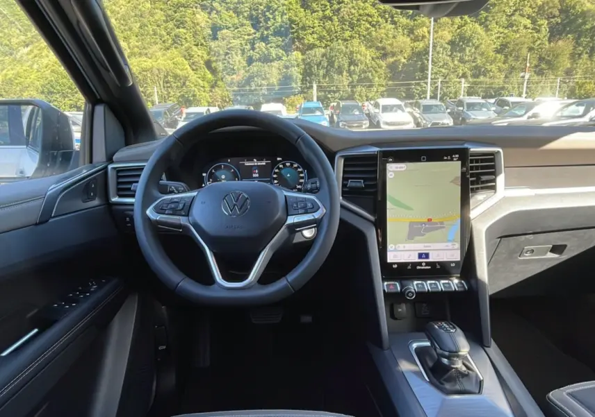Vue intérieure avant du Volkswagen Amarok blanc 2026, volant cuir multifonctions et écran tactile vertical.