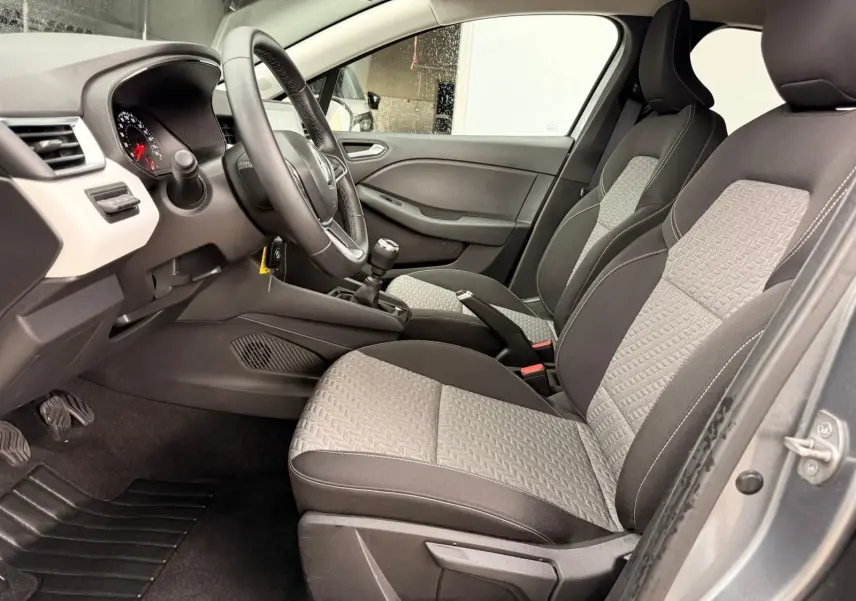 Vue intérieure avant de la Renault Clio V 1.0 TCE 90 Evolution avec tableau de bord noir et blanc et levier de vitesse manuel.