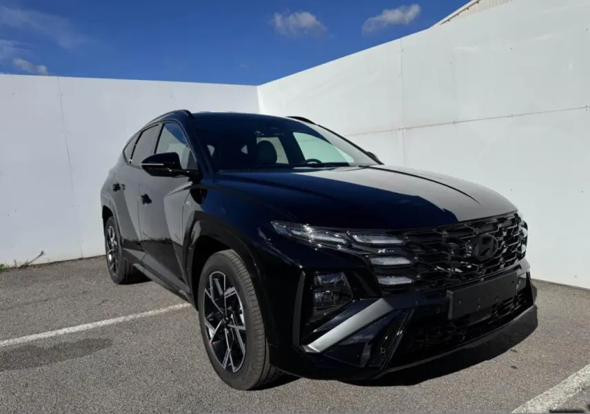 Hyundai Tucson IV noir abyss métal en 3/4 avant droit, avec calandre N Line et jantes alliage 19 pouces.