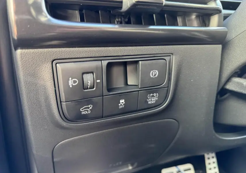 Gros plan sur les commandes côté gauche du tableau de bord du Hyundai Tucson noir, avec régulateur de frein de parking et ajustement des phares.