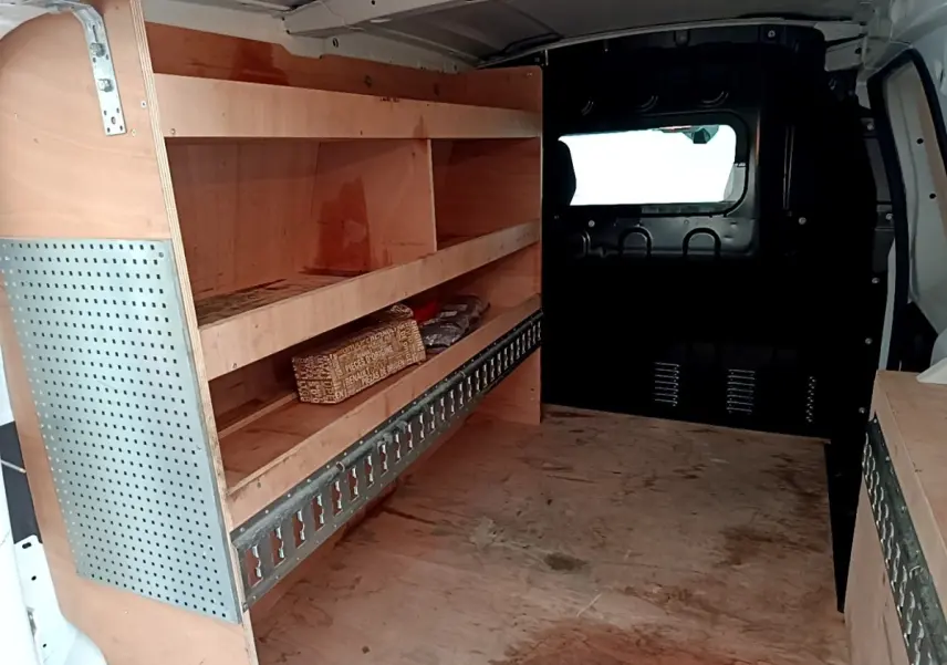 Intérieur du Renault Express blanc vu de l’arrière, montrant les étagères en bois et la cloison pleine vitrée.