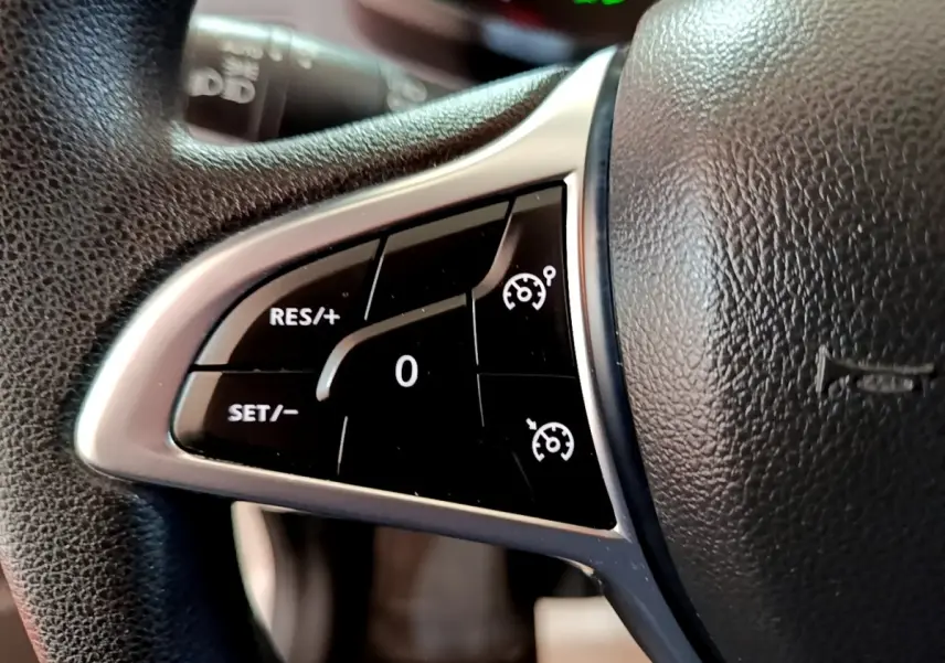 Gros plan sur les commandes de régulateur de vitesse au volant noir texturé du Renault Express blanc 2021.