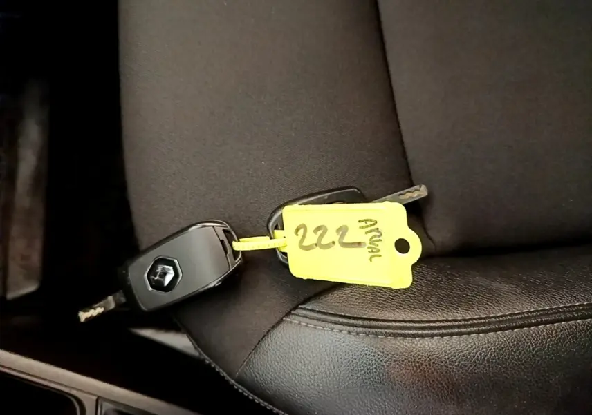 Clé de voiture Renault Express blanche posée sur un siège noir, vue rapprochée de l'intérieur.
