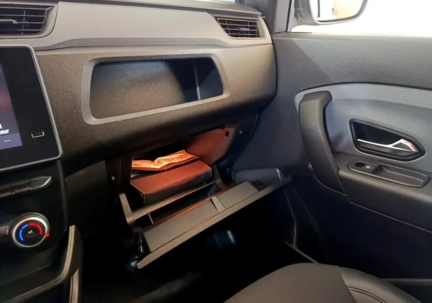 Intérieur noir du Renault Express 2021, vue côté passager avec boîte à gants ouverte et porte avec poignée visible.