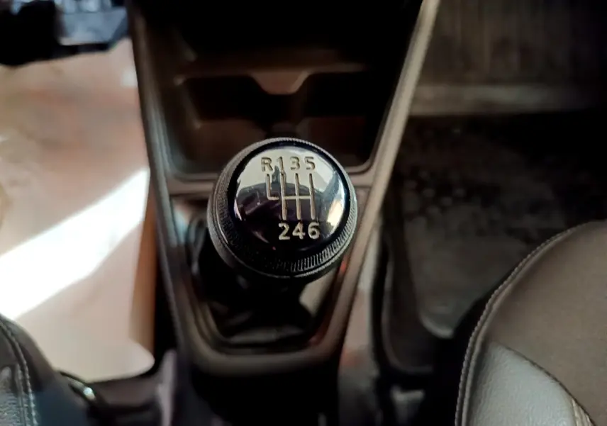 Gros plan sur le levier de vitesses manuel noir de la Renault Express Confort 2021, intérieur sombre.