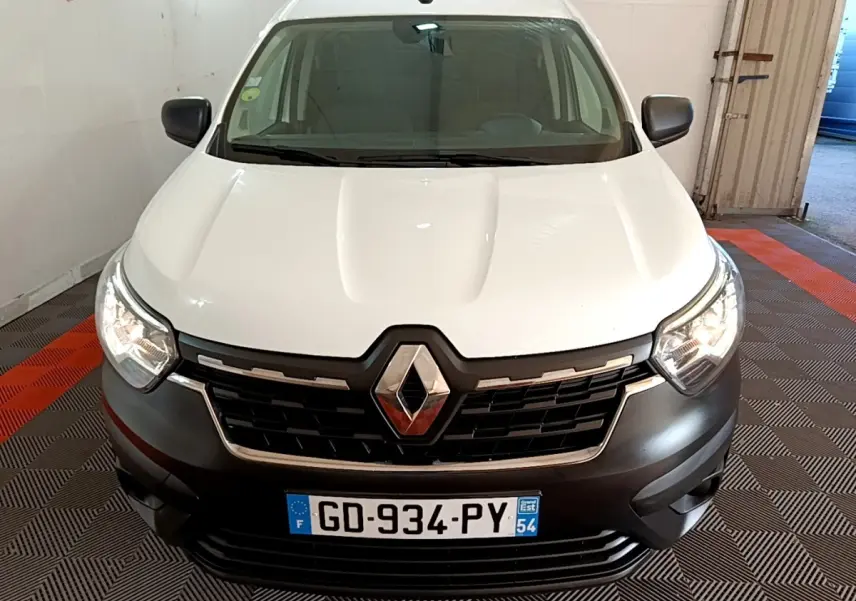 Vue avant d’un Renault Express blanc avec calandre noire et phares allumés dans un garage.