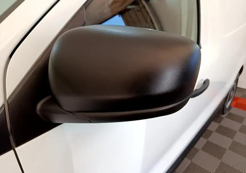 Gros plan sur le rétroviseur noir côté gauche du Renault Express blanc, avec poignée de porte visible.