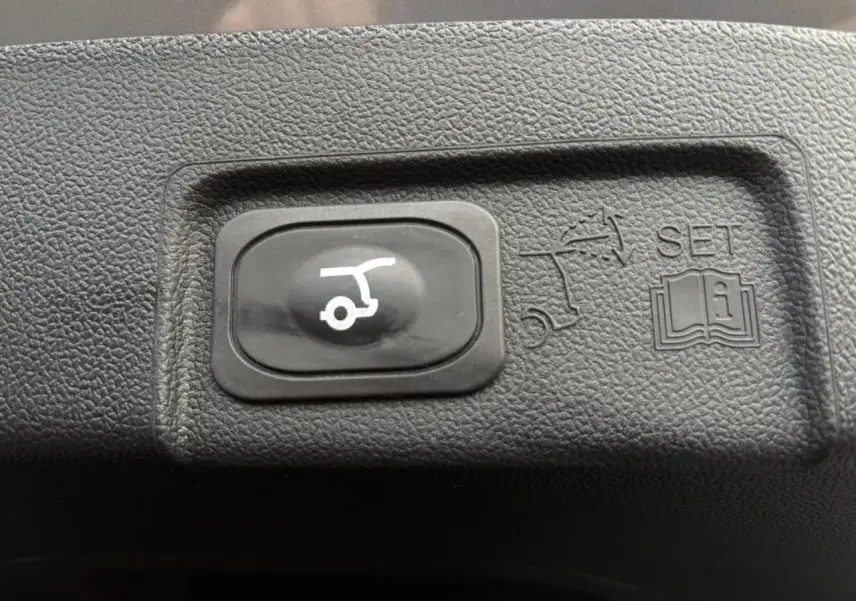 Bouton noir de hayon électrique avec pictogramme blanc sur plastique texturé intérieur d'un Ford Puma gris Solar 2023.