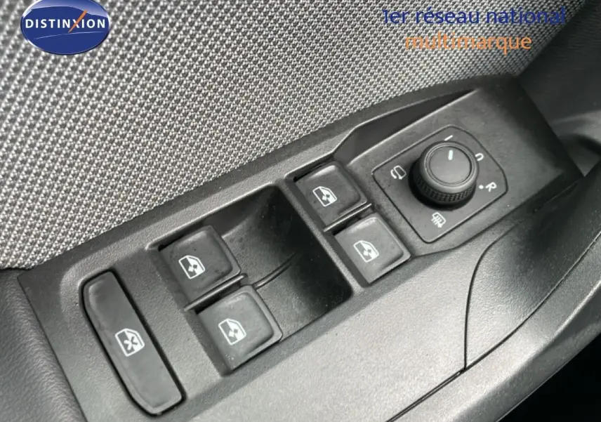 Gros plan sur les commandes des vitres et rétroviseurs côté conducteur d’une SEAT Leon bleu Fjord 2025.