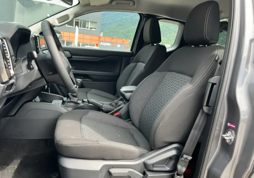Vue intérieure côté conducteur du Ford Ranger gris carbone 2025, montrant les sièges tissu et le volant multifonctions cuir.