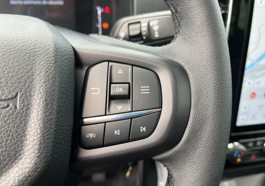 Gros plan sur les commandes multifonctions à gauche du volant cuir noir du Ford Ranger gris carbone 2025.