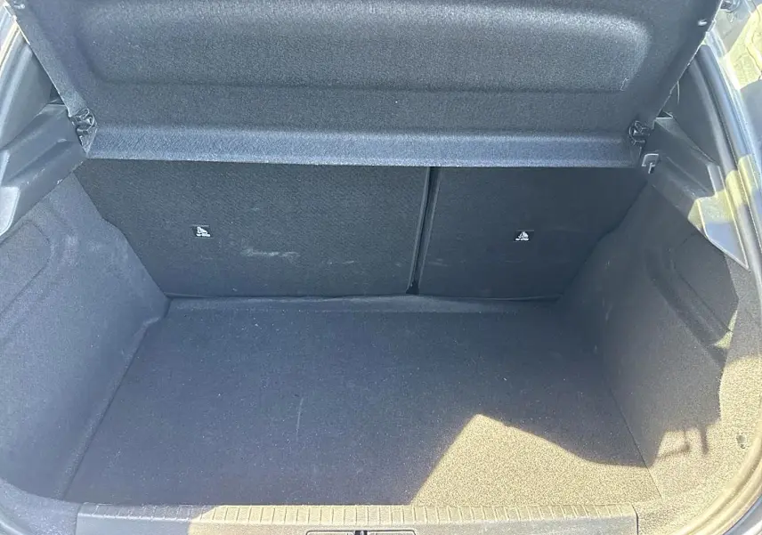 Coffre ouvert de la Peugeot 208 gris artense, montrant un espace de rangement propre et spacieux.