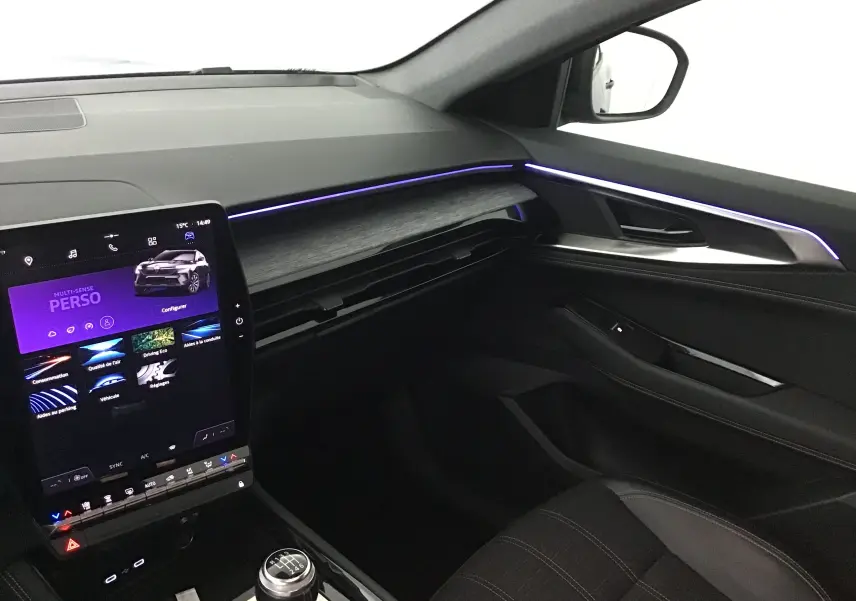 Intérieur côté passager du Renault Austral 2023 bleu iron/noir, avec tableau de bord numérique et éclairage d'ambiance violet.