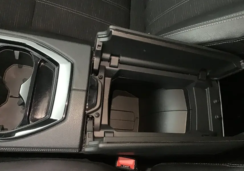 Vue plongeante sur la console centrale ouverte du Renault Austral 2023, avec porte-gobelets et sellerie noire.