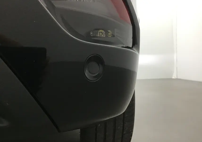 Gros plan sur le pare-chocs arrière côté droit du Renault Austral bleu iron/noir, avec feu arrière et capteur de stationnement visible.