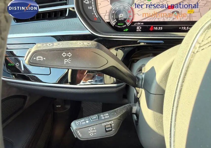 Gros plan sur les commandes au volant d'une Audi A8 noire, avec affichage numérique et fonctions d'assistance visibles.
