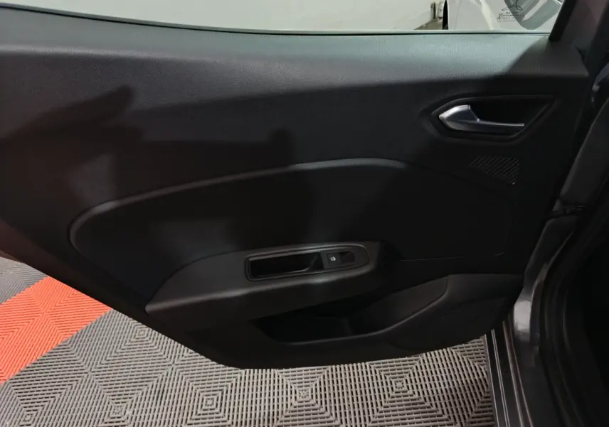 Vue intérieure de la porte côté gauche d'une Renault Clio gris foncé, avec poignée et commande de vitre électrique.