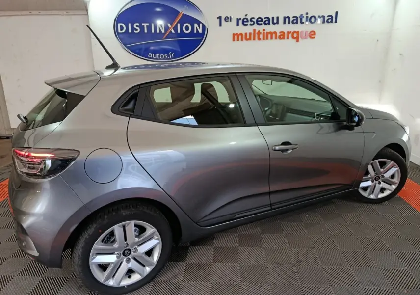 Profil côté gauche d'une Renault Clio gris foncé 2025 garée en intérieur avec jantes alliage et feux arrière LED allumés.