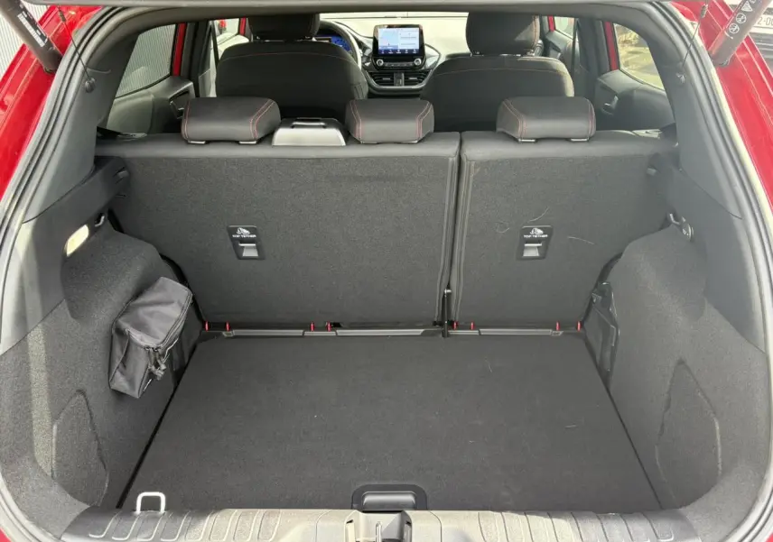 Vue arrière du coffre spacieux du Ford Puma rouge Fantastic 2023 avec sièges arrière et tableau de bord visibles.