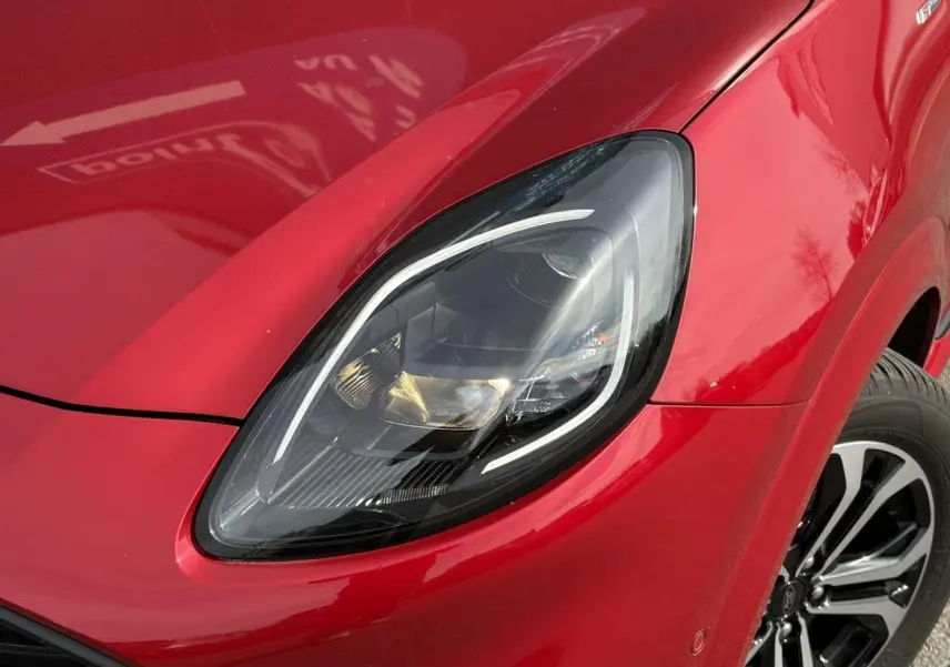 Gros plan sur le phare avant gauche du Ford Puma Ecoboost 155 BVA ST Line rouge Fantastic avec jante alliage 17 pouces.