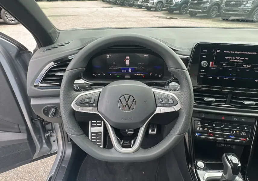 Vue intérieure centrée sur le volant multifonctions cuir du Volkswagen T-Roc gris pyrite avec tableau de bord digital.