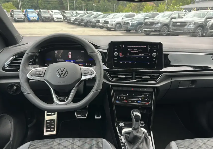 Vue intérieure du tableau de bord du Volkswagen T-Roc 2025 avec volant multifonctions et écran tactile central.