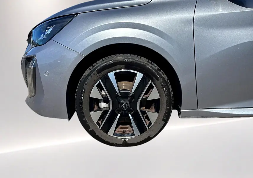 Gros plan sur la roue avant gauche d’une Peugeot 208 gris artense avec jante alu au design moderne.