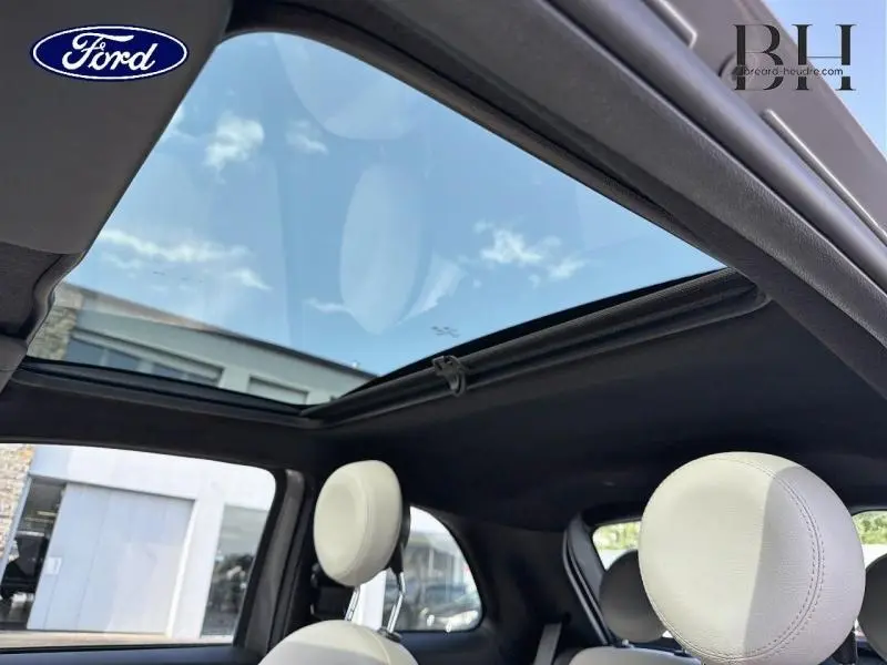 Vue intérieure montrant le toit panoramique en verre et les appuie-têtes blancs d'une Fiat 500 Electroclash Grey.
