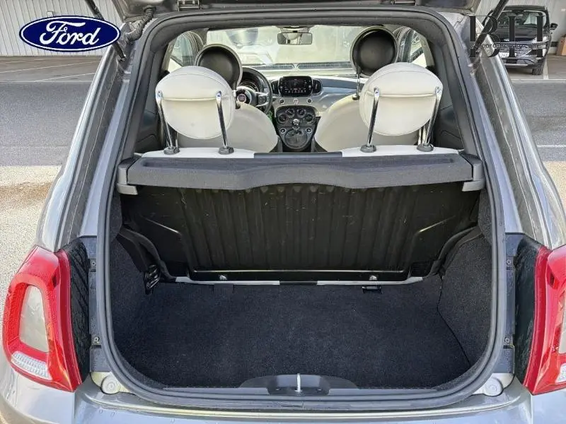 Coffre ouvert vu de l'arrière d'une FIAT 500 Electroclash Grey Métal, sièges blancs et tableau de bord visible.