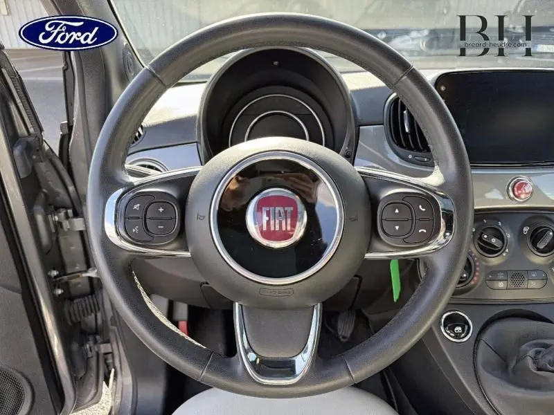Vue intérieure centrée sur le volant cuir multifonction d'une Fiat 500 2022, avec tableau de bord et commandes visibles.