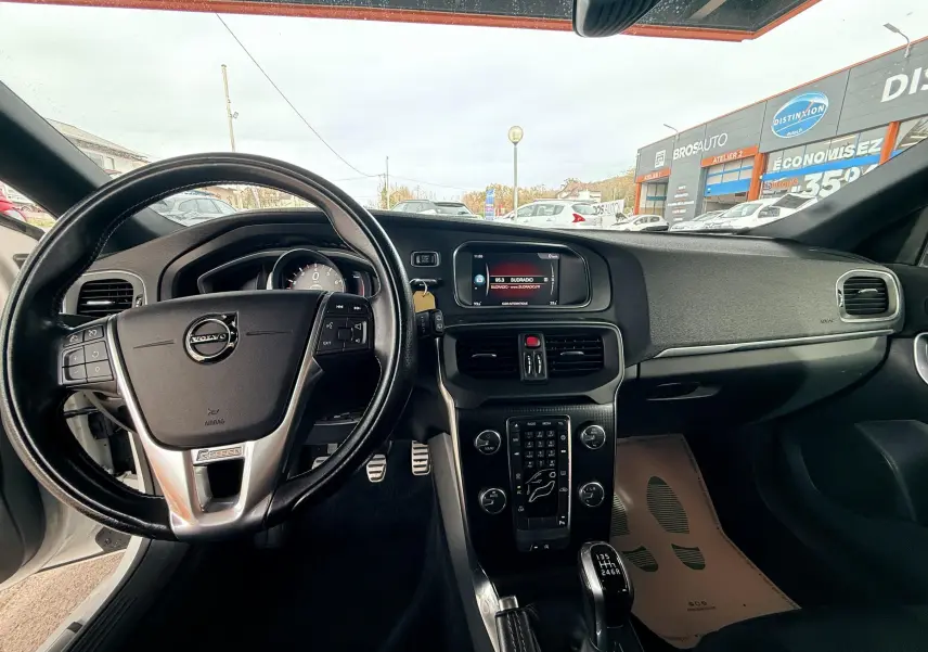Intérieur de Volvo V40 R-Design 2017 vu côté conducteur, volant cuir noir et console centrale avec boîte manuelle.