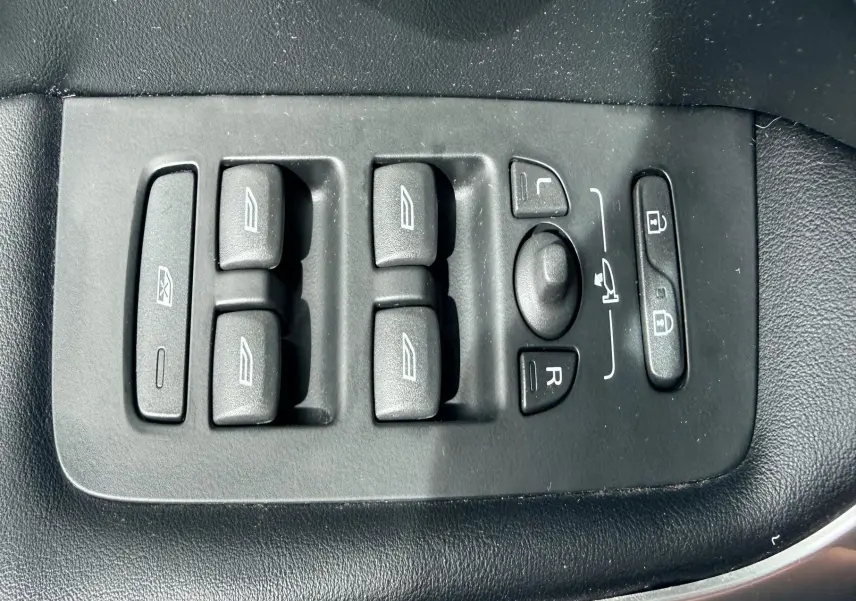 Panneau de commandes des vitres et rétroviseurs côté conducteur d'une Volvo V40 R-Design blanche, intérieur noir.