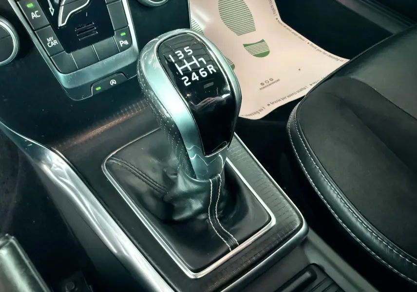 Le levier de vitesses manuel noir et argenté du Volvo V40 R-Design 2017, avec coutures blanches visibles sur la console centrale.
