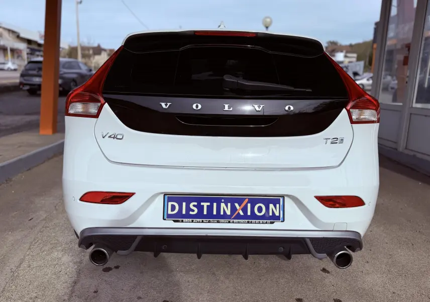 Vue arrière d'une Volvo V40 blanche 2017 avec logo noir brillant et double sortie d'échappement chromée.