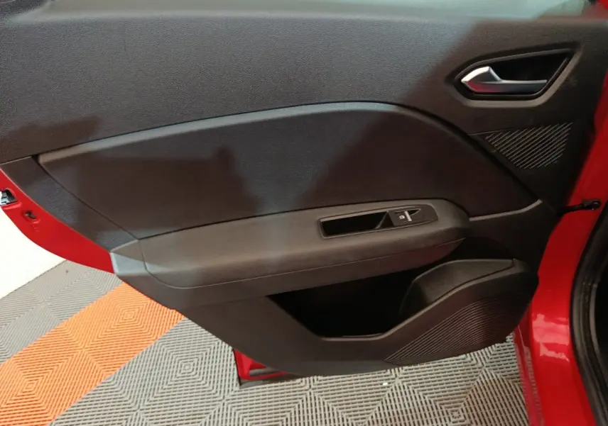 Porte intérieure côté gauche noire du Renault Captur rouge 2024, avec poignée argentée et commande de vitre électrique.
