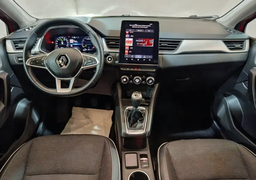 Vue intérieure avant du Renault Captur techno TCe 90 2024, tableau de bord avec écran tactile vertical et boîte manuelle.